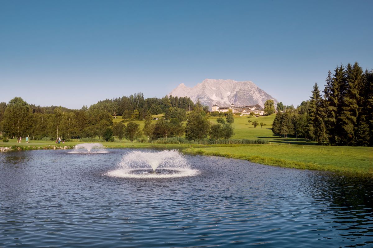 Golfplatz_Teich_IMLAUER Hotel Schloss Pichlarn klein Teich mit Fontänen am Golf & Country Club Schloss Pichlarn, im Hintergrund IMLAUER Hotel Schloss Pichlarn