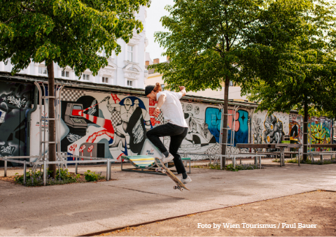 Street-art-1 Skateboarder in einem Wiener Stadtpark vor Graffiti.